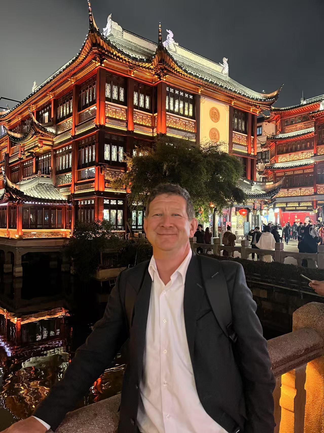 Steve Kooy smiling in front of illuminated traditional architecture at night